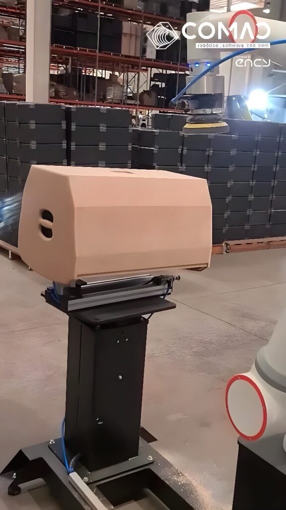 Collaborative robot arm with pneumatic orbital sander finishing a clamped wood-composite enclosure, generating sanding dust