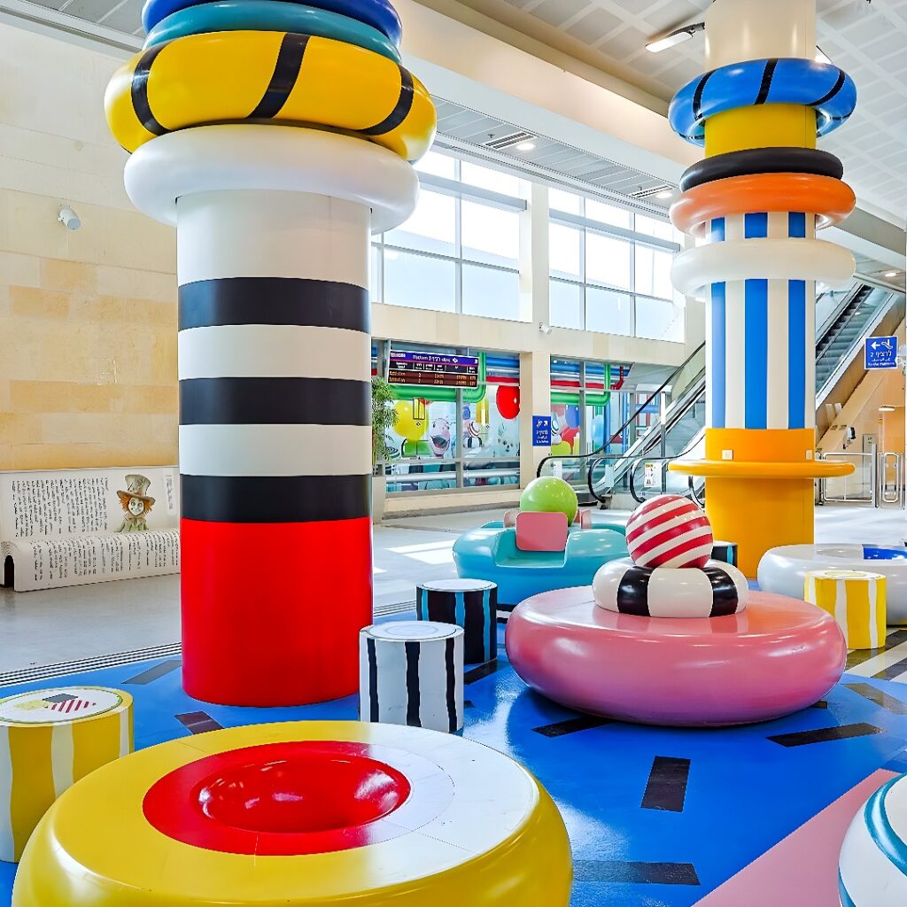 Several large toroidal foam or composite rings with visible layer lines on the floor of a workshop, surrounded by tables and material drums.