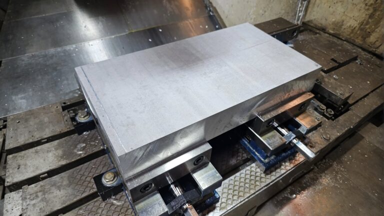 Close-up of a metal billet secured in a CNC milling machine during machining