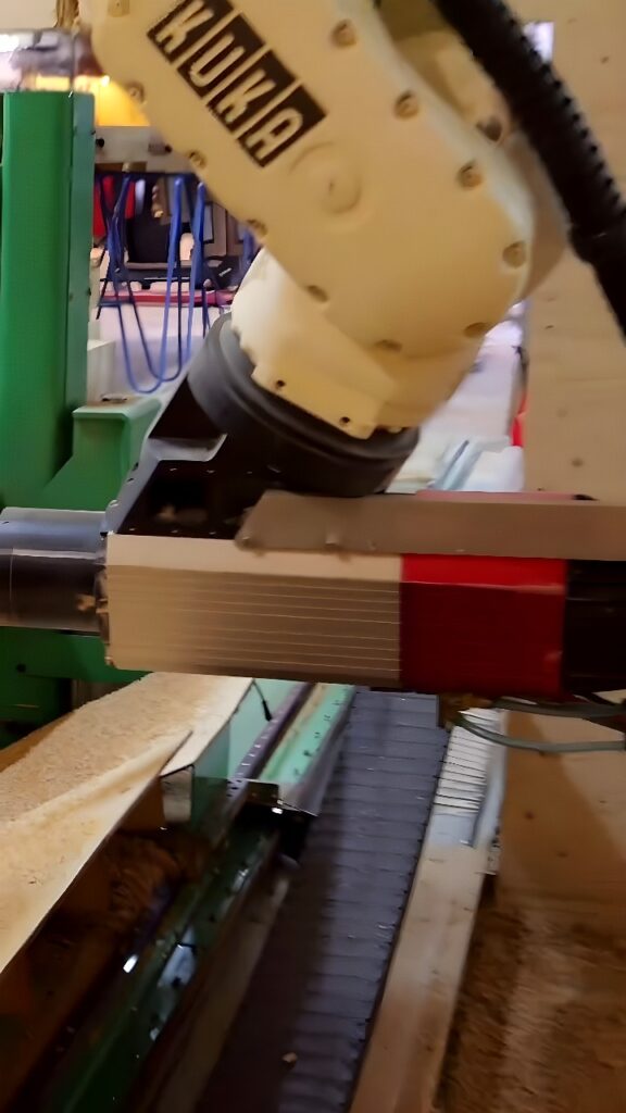 KUKA industrial robot arm with spindle end mill routing a wooden board on a CNC worktable