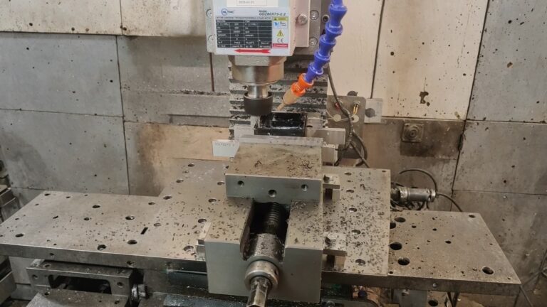 CNC milling spindle cutting a metal workpiece with coolant and metal chips